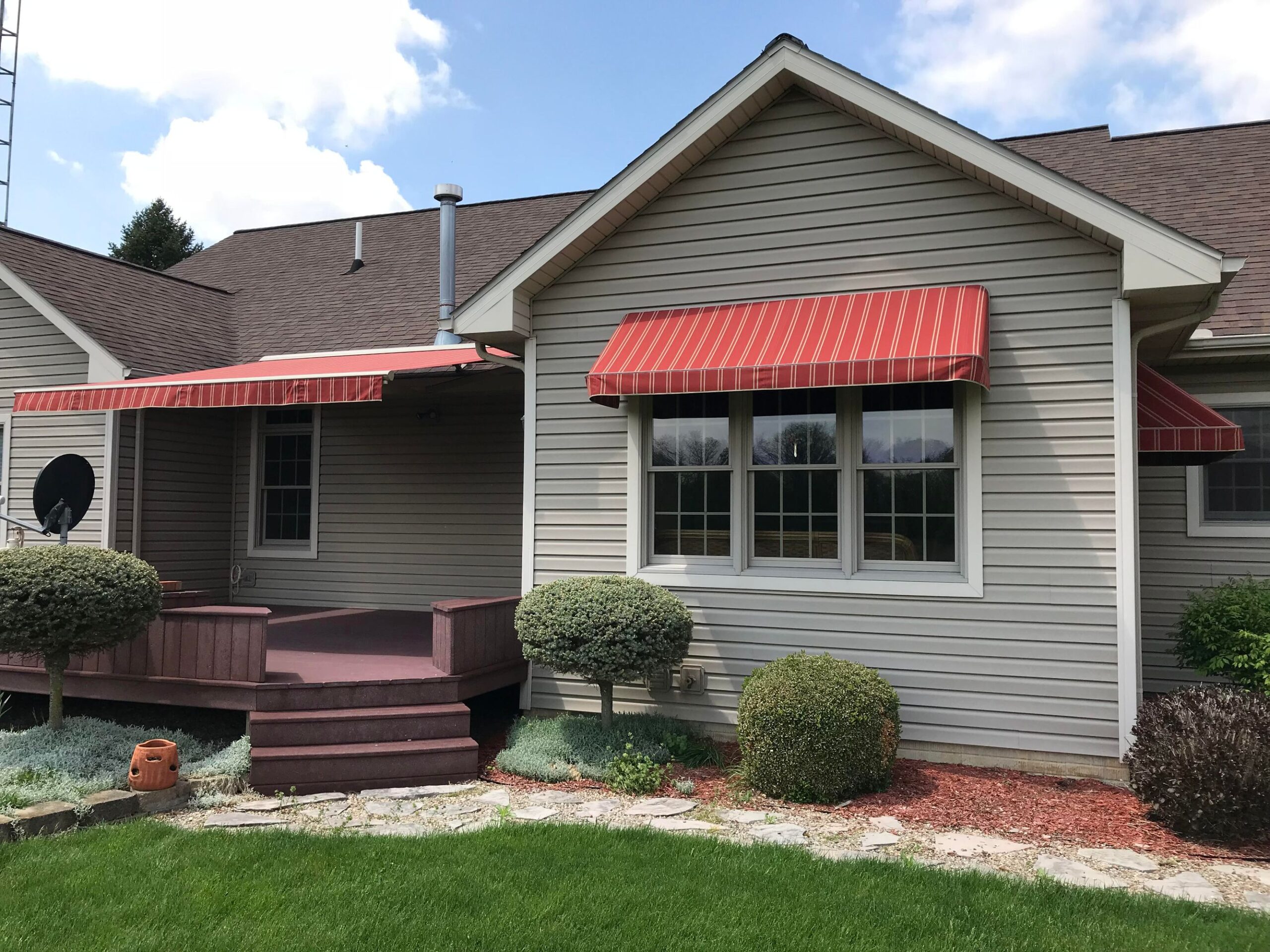 A lovely house showcasing a vibrant red awning and a spacious porch