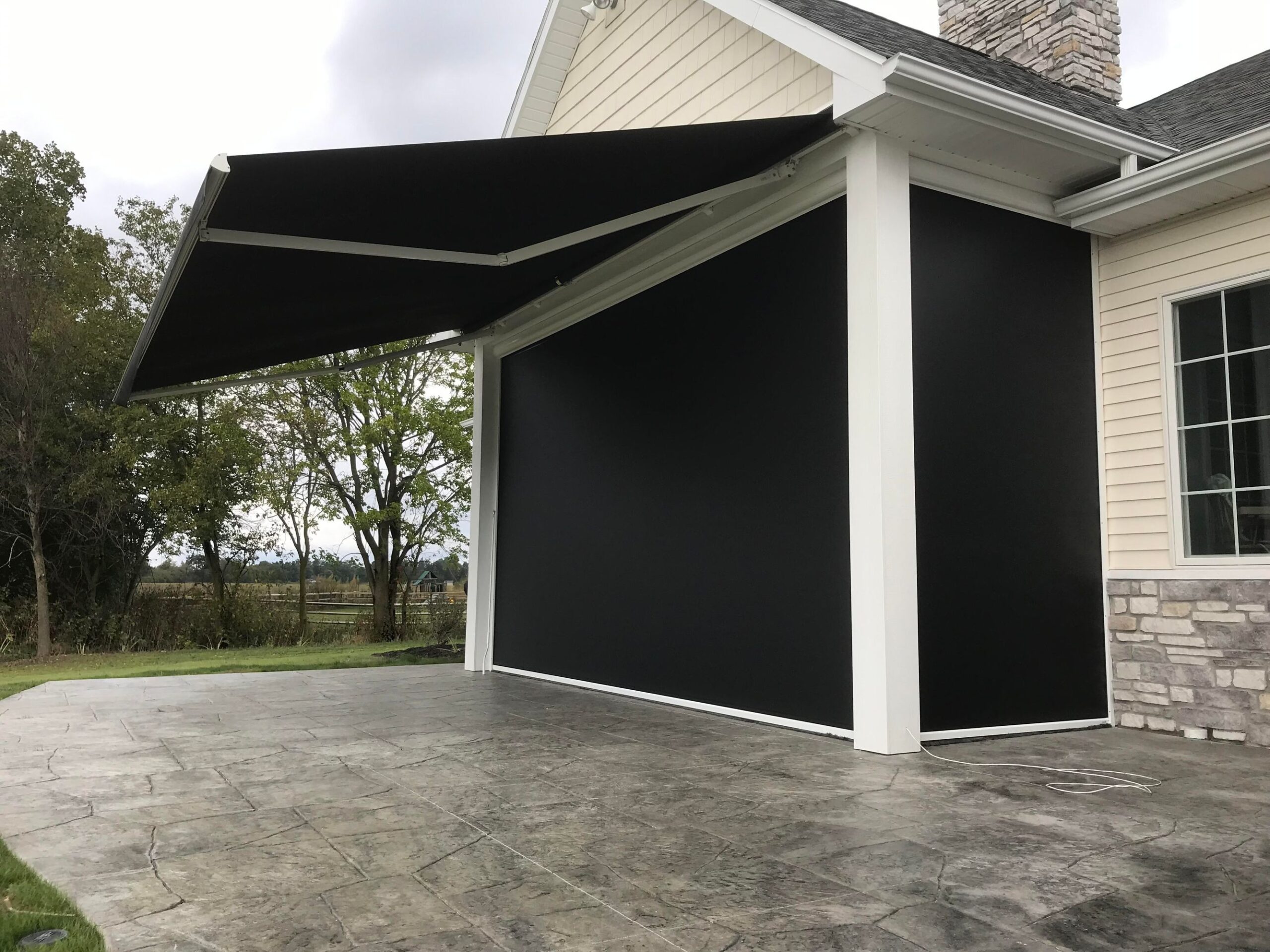 A black awning extends from the side of a house, providing shade and enhancing the exterior design